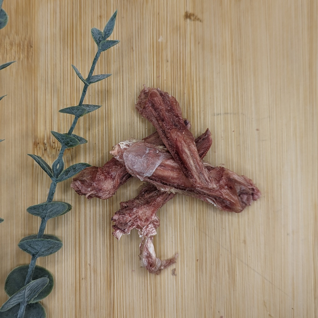 A protein-rich piece of Freeze-dried Duck Tongues 1oz, packed with zinc, artfully displayed on a polished wooden surface from Beast Feast.