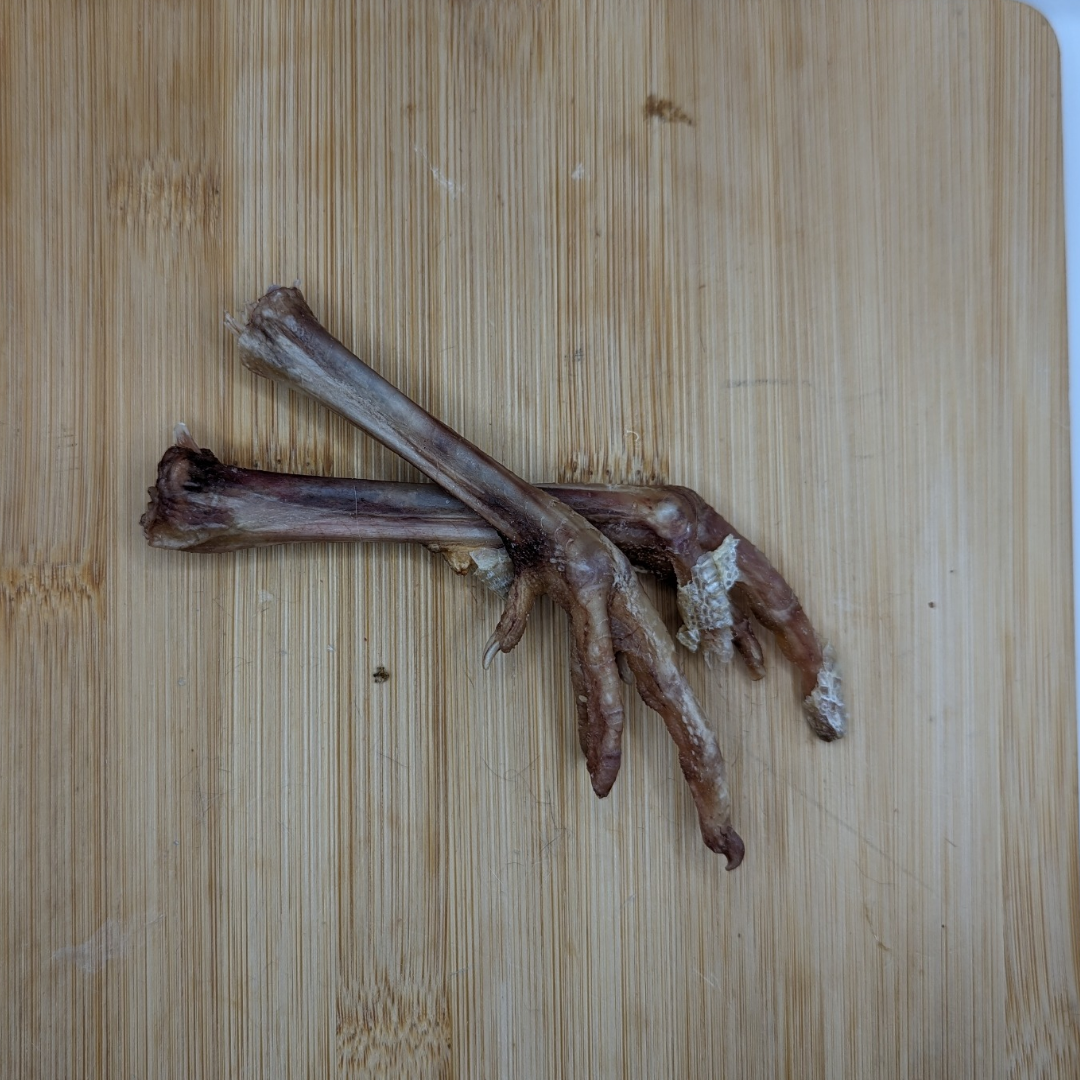 A pair of Beast Feast freeze-dried Pheasant Feet on a cutting board.