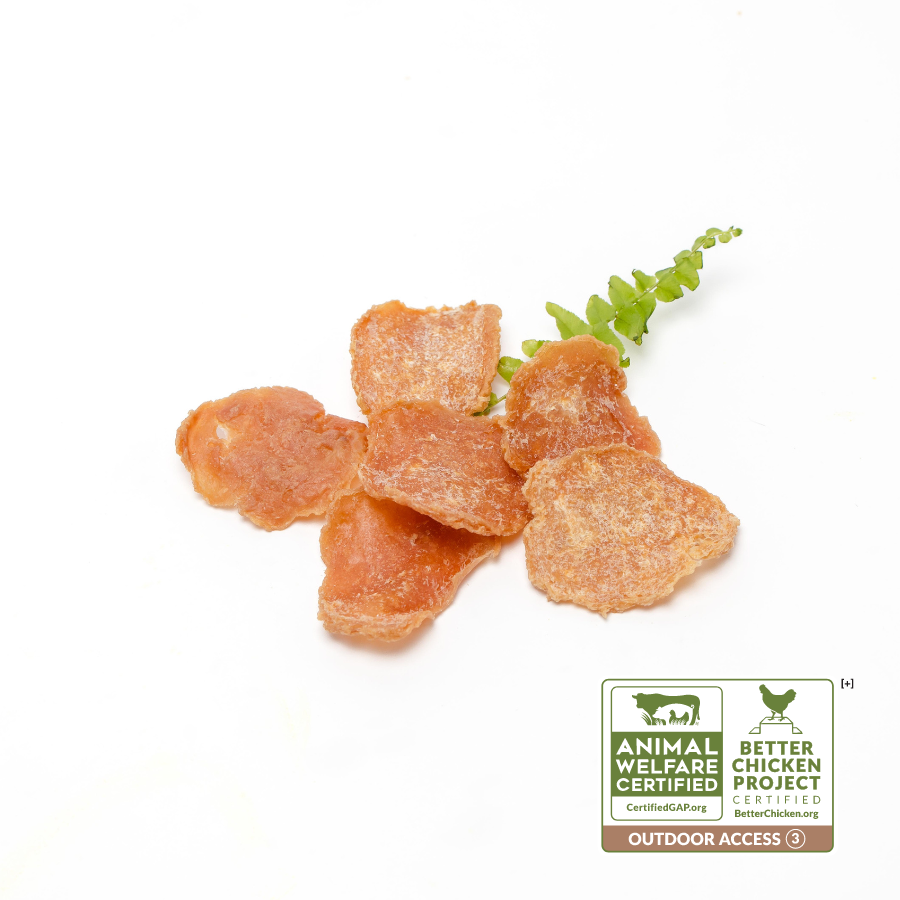Dried Chicken Crispers 1 oz chunks placed next to a sprig of green leaves on a white background, with animal welfare and certification logos displayed, make a healthy treat for pets from Beast Feast.