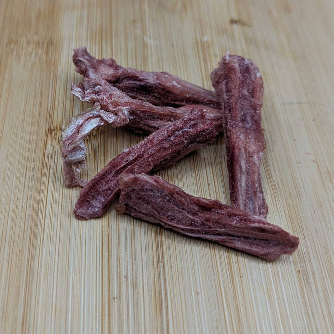 A 1oz packet of Beast Feast Freeze-dried Duck Tongues is sitting on top of a wooden surface.