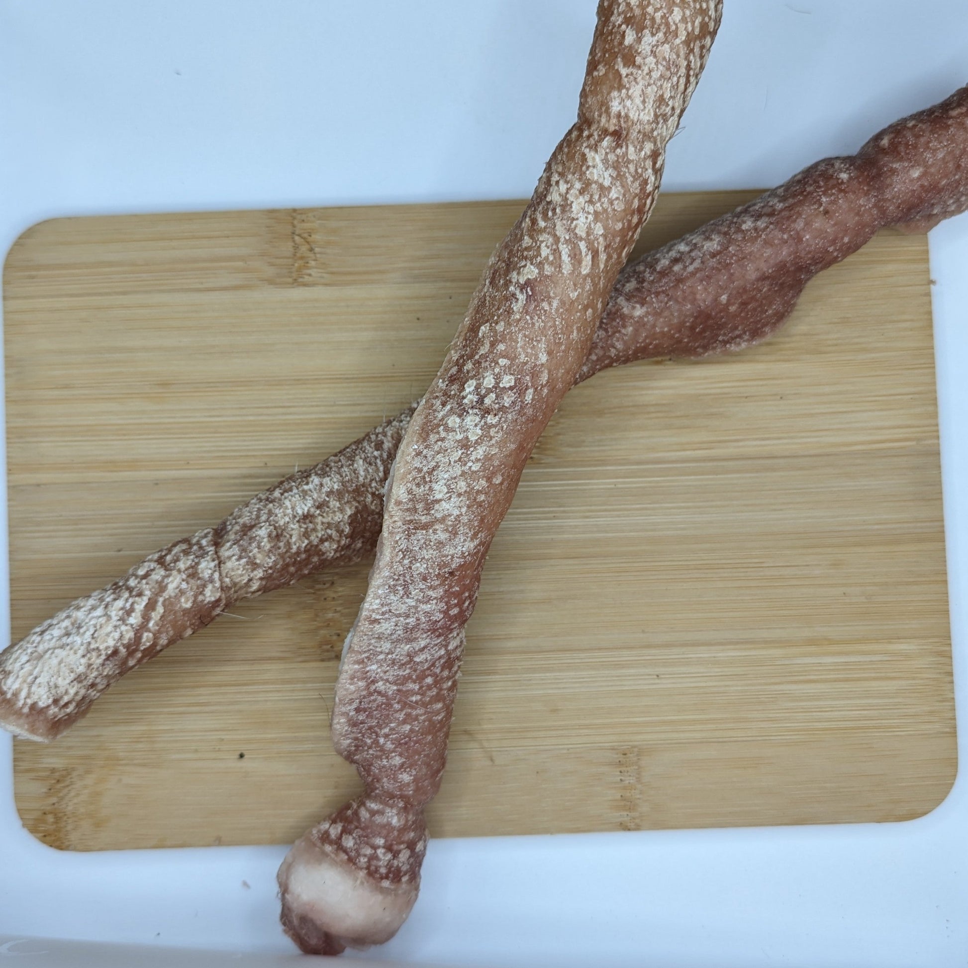 A wooden cutting board with two sticks on it is perfect for slicing Beast Feast's Heritage Breed Freeze-dried Pork Rolls.