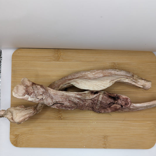 Freeze-Dried Bison Tibial Tendon slices from Beast Feast on a wooden chopping board next to a knife, ideal for joint health and a chew for puppies.