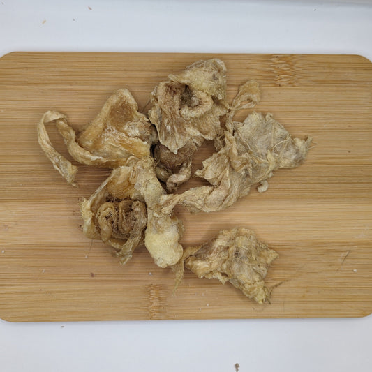 Freeze-Dried Chicken Collagen Chomps 3oz from Beast Feast scattered on a wooden cutting board.