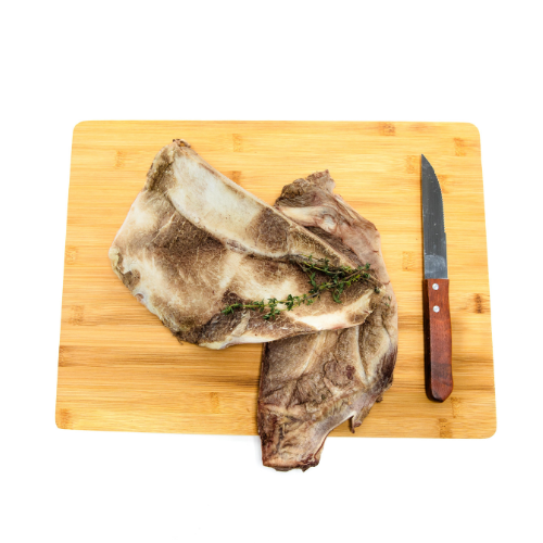 A Freeze-Dried Bison Scapula on a cutting board with a knife, perfect for senior dogs or teething puppies from Beast Feast.